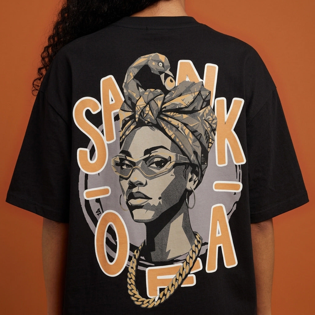 Blackness Sankofa Queen Tee, black — close-up of the Sankofa back print worn, terracotta backdrop