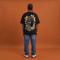 Blackness Sankofa King Tee, black, worn by a model — back view, Sankofa woven hat portrait print, terracotta backdrop