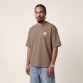 Wear Blackness Tee Brown worn by model, front view with Wear Blackness chest print on warm ivory studio backdrop