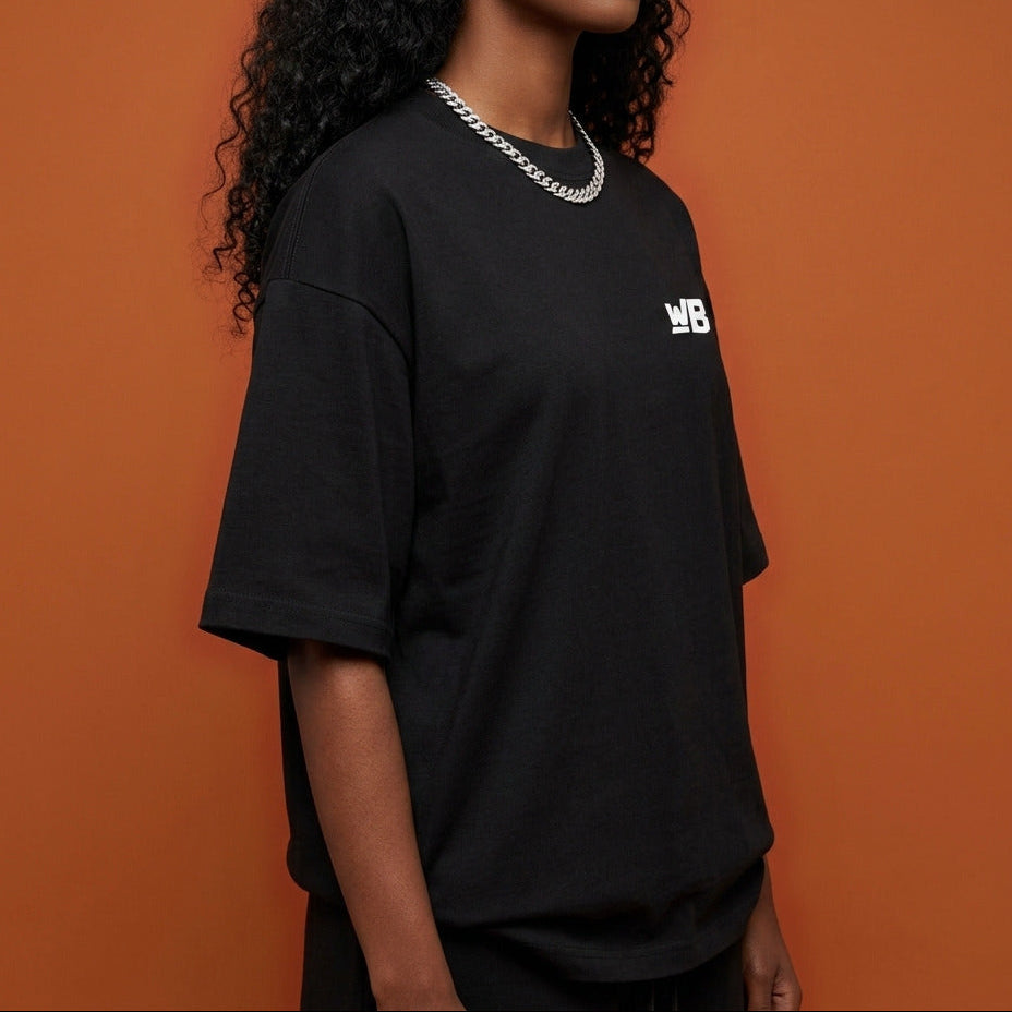 Blackness Sankofa Queen Tee, black — shoulder and collar detail, side view, terracotta backdrop