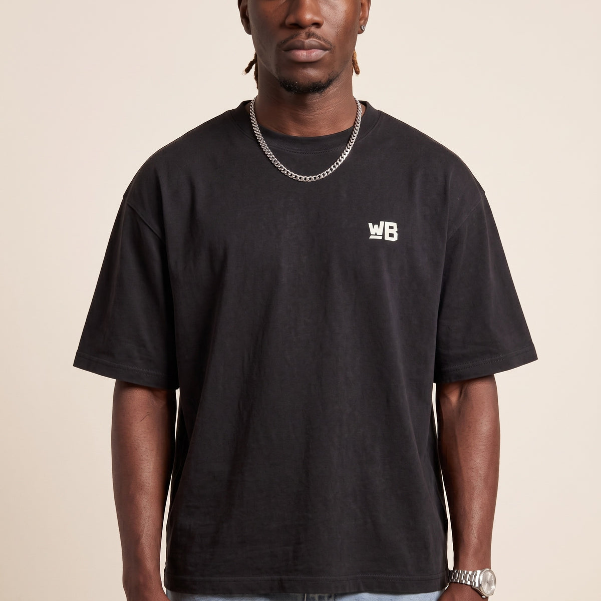 Base Blackness Tee Black — close-up of the WB monogram chest logo and ribbed collar, oversized heavyweight cotton streetwear tee by We Are Blackness