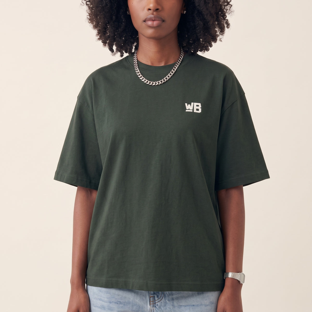 Base Blackness Tee Green — close-up of the WB monogram chest logo and ribbed collar, oversized heavyweight cotton streetwear tee by We Are Blackness