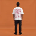 Blackness Mawon Tee, white, worn by a model — back view, Neg Mawon conch-blower block print, terracotta-orange studio backdrop