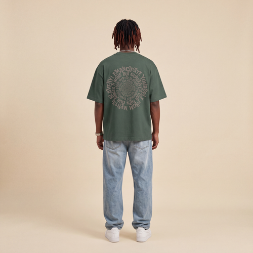 Blackness Emancipation Tee Cactus Green worn by model, back view showing the spiral Emancipate Yourself print on beige studio backdrop