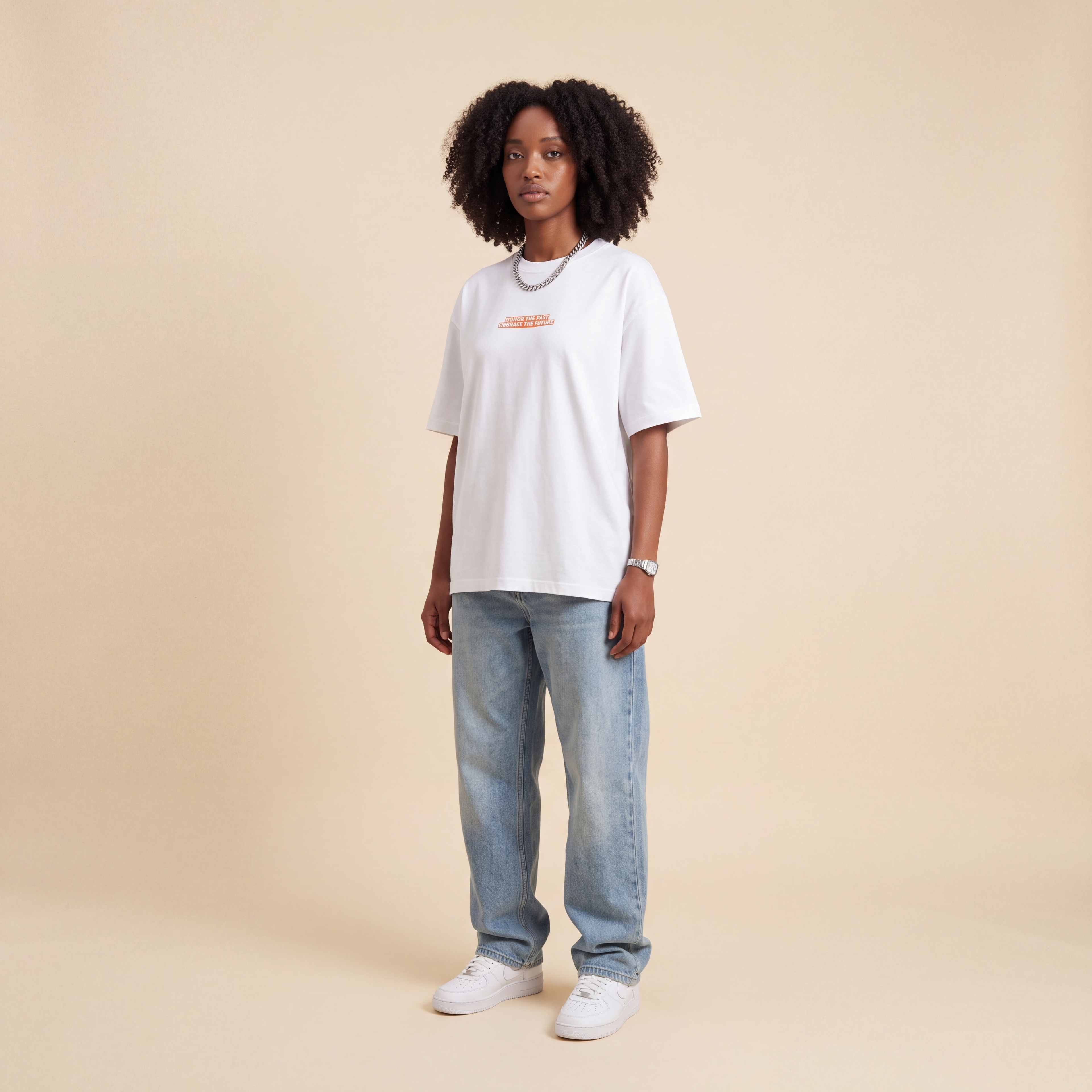 Blackness Honor & Embrace Tee White worn by model, front view with the Honor The Past Embrace The Future chest print on beige studio backdrop