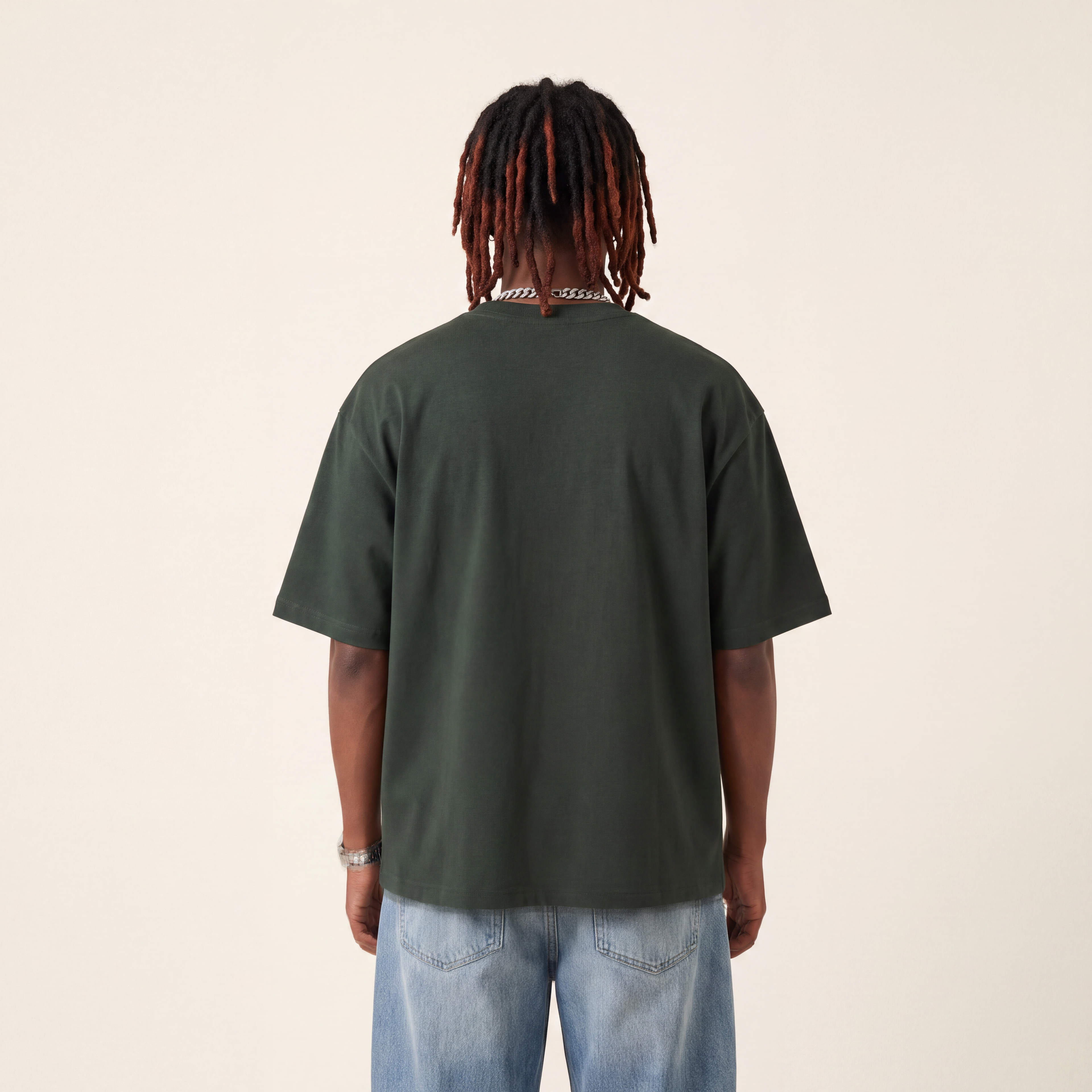 Wear Blackness Tee Green worn by model, back view showing the clean plain back on warm ivory studio backdrop
