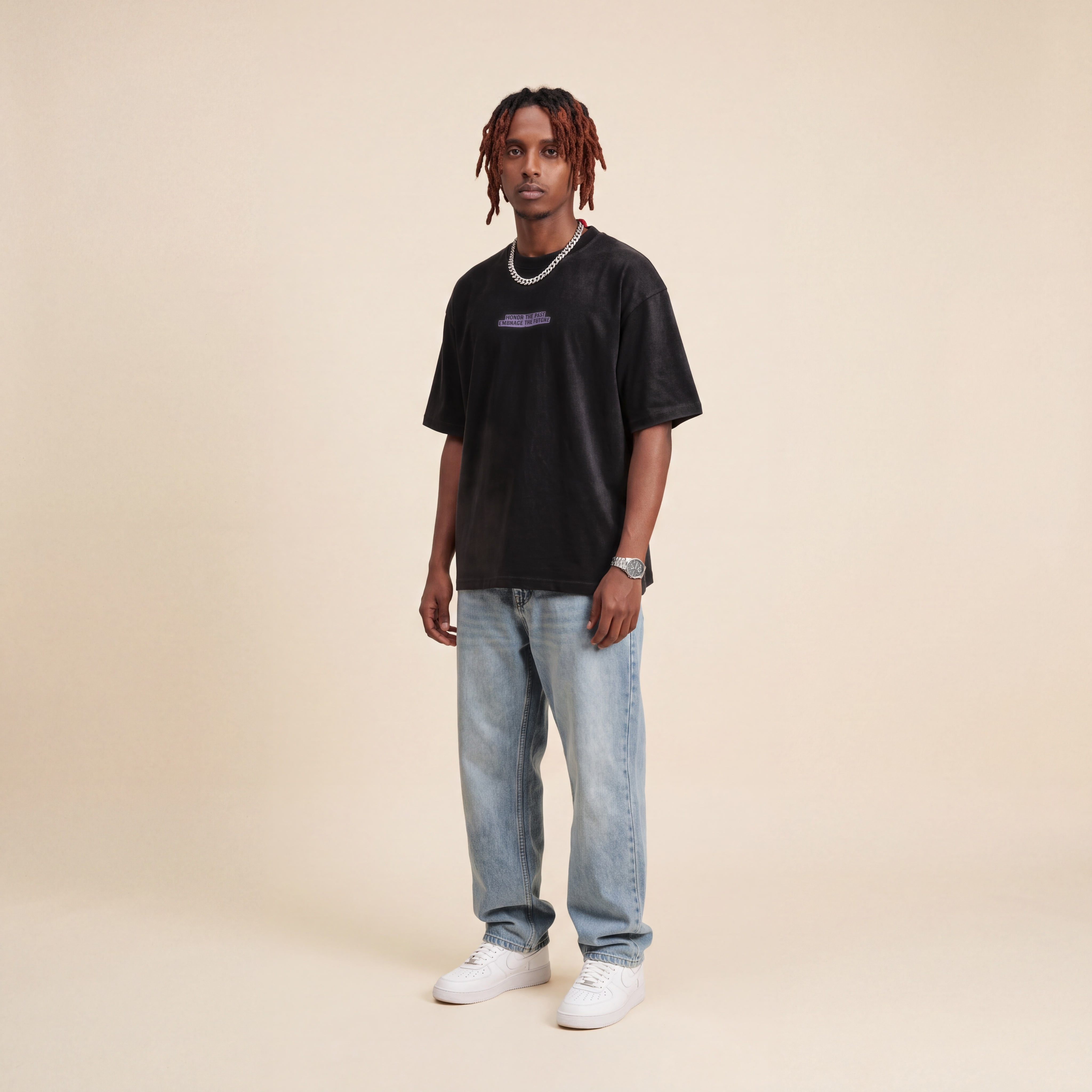 Blackness Honor & Embrace Tee Black worn by model, front view with the Honor The Past Embrace The Future chest print on beige studio backdrop